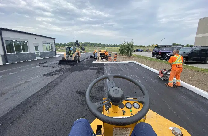 Workers paving an asphalt parking lot in Whitby, ON.