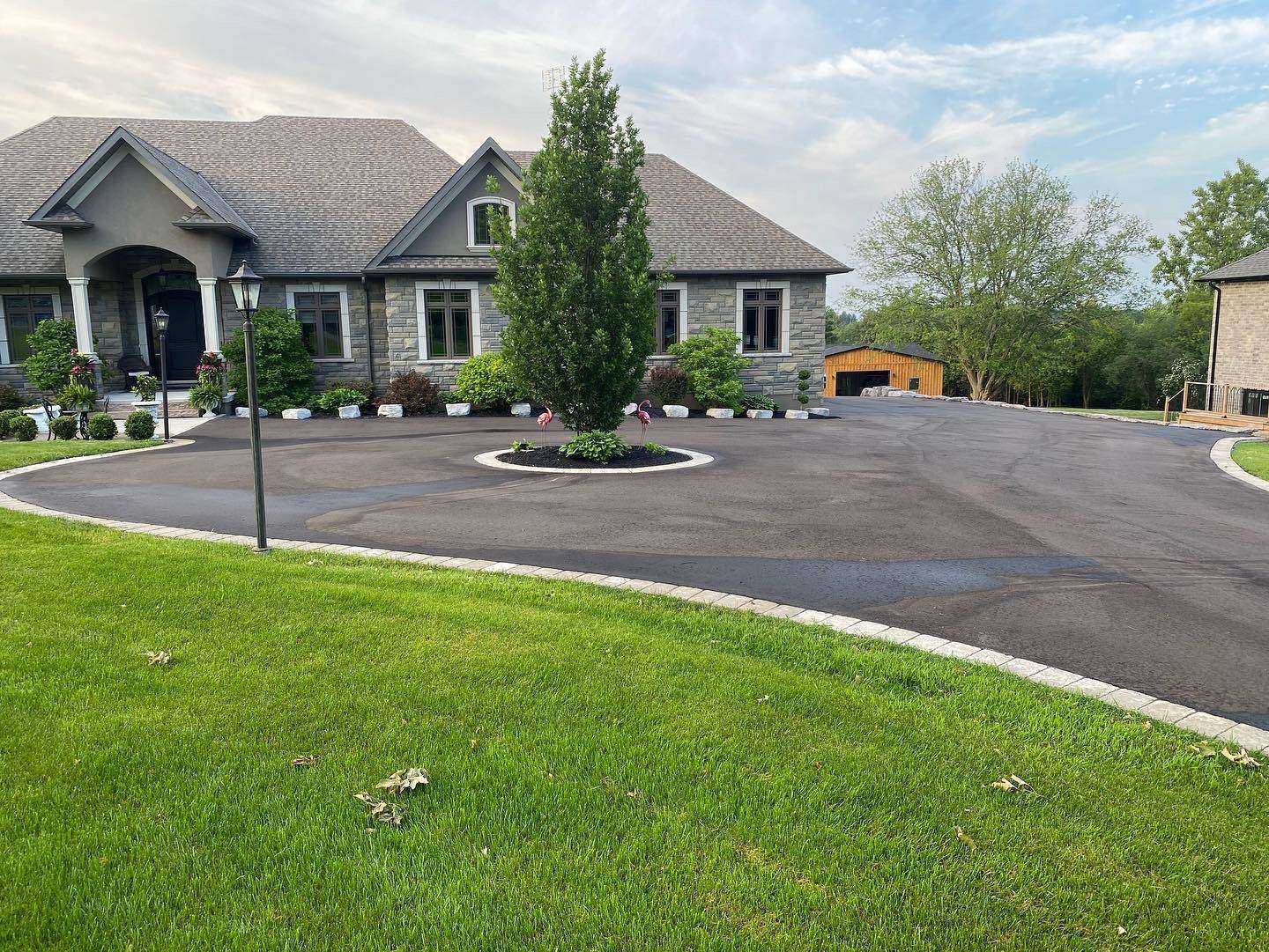Smooth residential asphalt driveway with interlocking stone borders in a Whitby neighborhood.